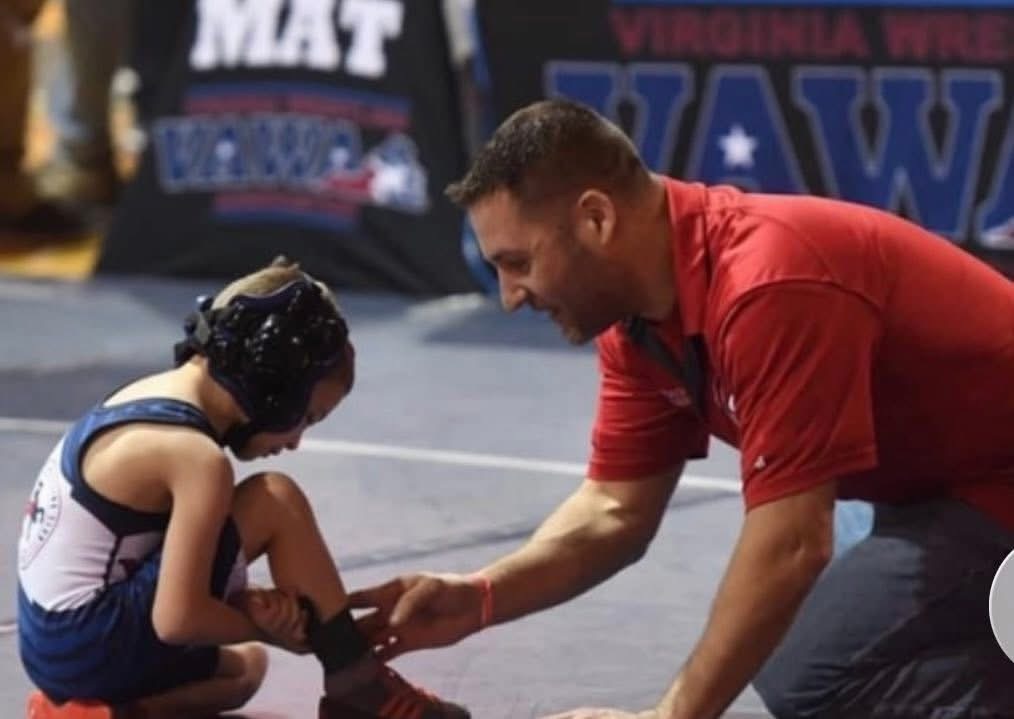 A coach helping a wrestler at a tournament