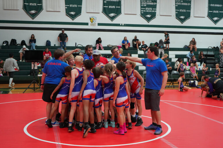 WWC wrestlers huddled with their coach before a tournament