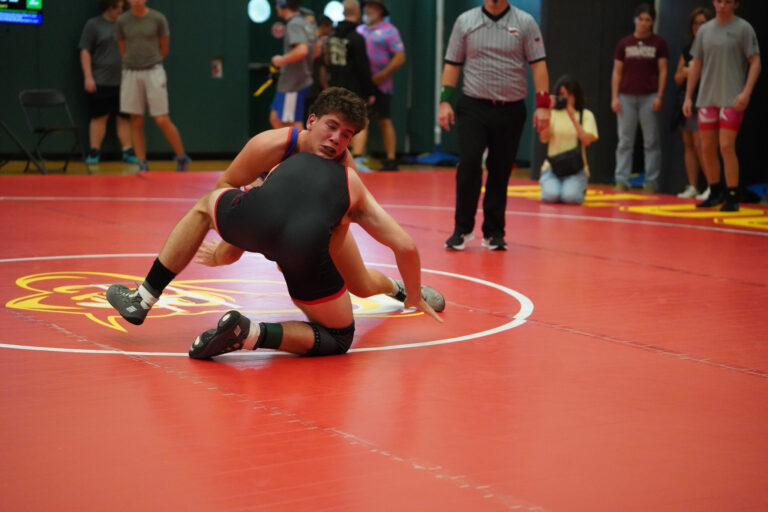 A wrestler in a match on a red mat